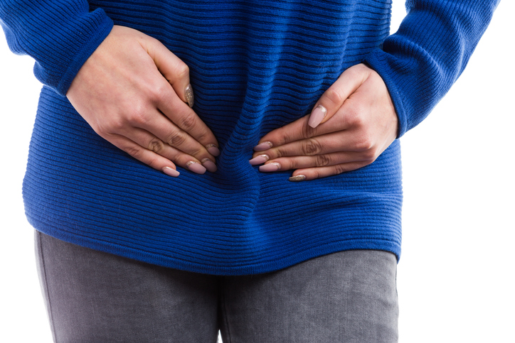 Close up of woman hands pressing painful lower abdomen as menstruation period ache concept isolated on white background