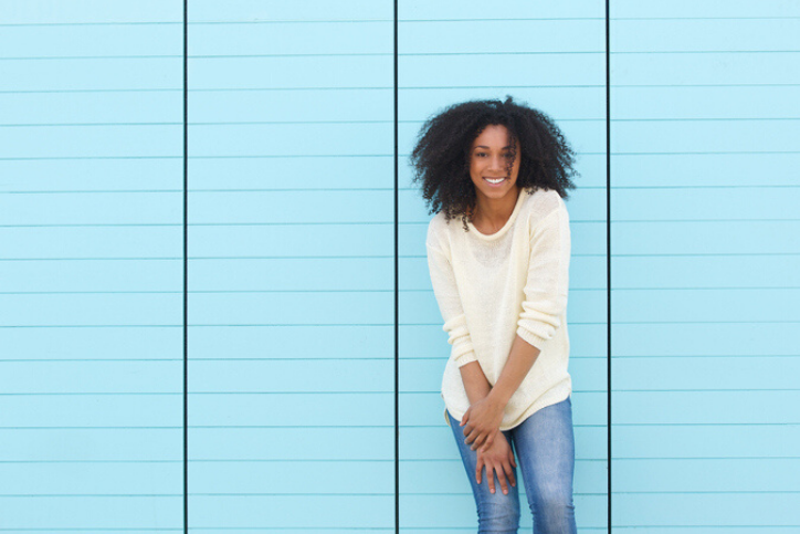 Young woman smiling on blue background