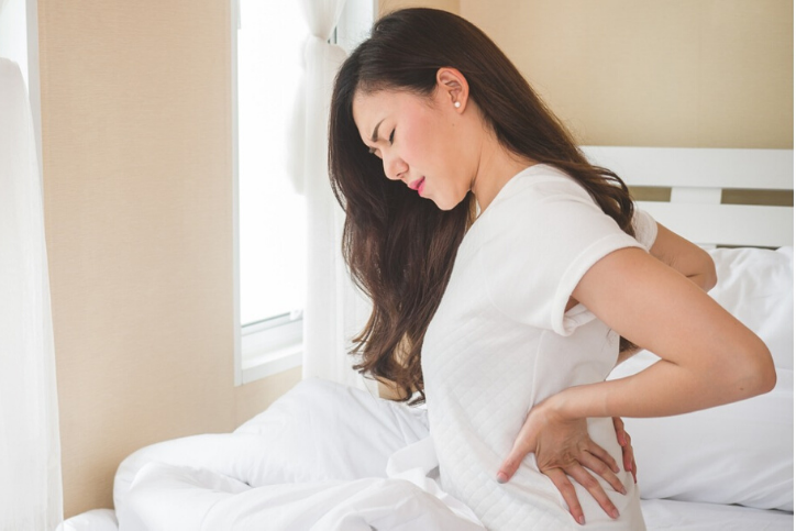 young-woman-having-back-ache-sitting-on-white-bed-picture, maybe having issues with uterine fibroids.