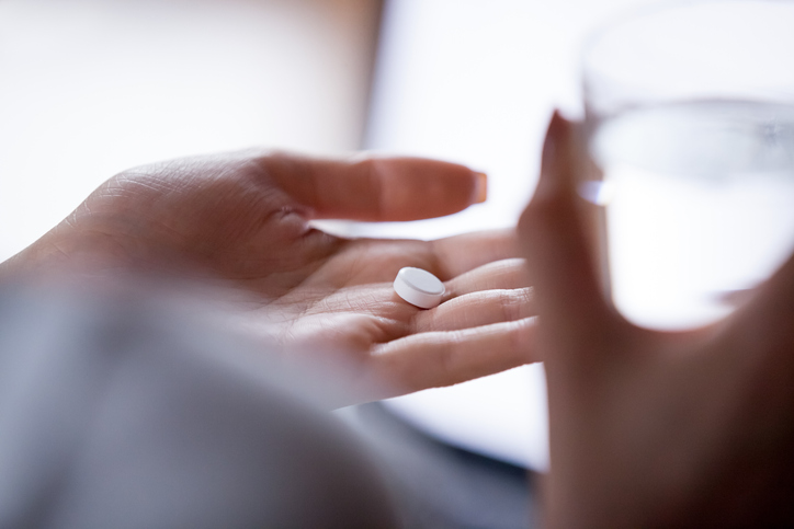 Close up woman holding hormone pellets in hand with water.