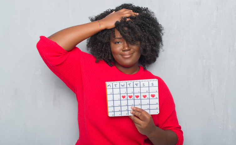 Black woman confused about when to see a doctor about abnormal menstrual cycles.