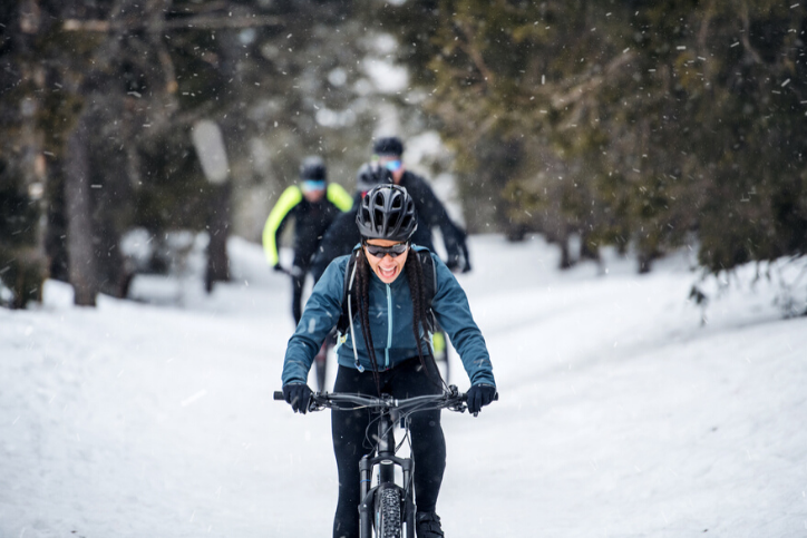 A group of young mountain bikers riding on road outdoors in winter, staying active this winter.