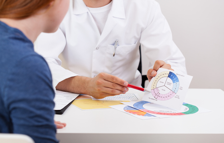 Male gynecologist explaining young girl menstrual period, discussing tubal ligation.