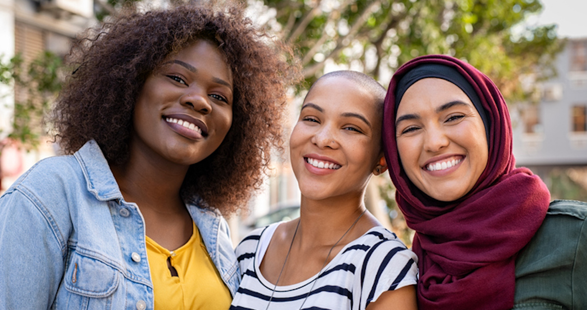 Group of three happy multiethnic friends looking at camera. Portrait of young women of different cultures enjoying vacation together. Smiling islamic girl with two african american friends outdoor., wondering about common Health Issues Women Face in their 20s
