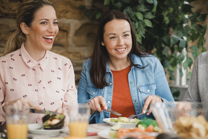 Two mid adult women listening and talking while eating a healthy meal, discussing Most Common Health Issues Women Face in their 30s.