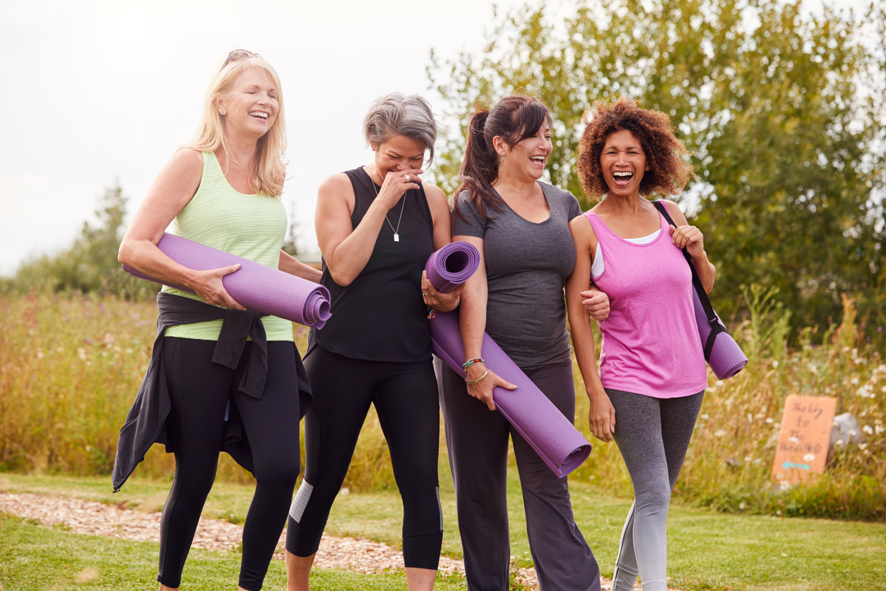 Group Of Mature Female Friends On Outdoor Yoga Retreat Walking Along Path Through Campsite, discussing Most Common Health Issues Women Face in Their 40s.