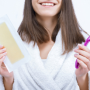 Portrait of young woman is choosing unwanted hair removal tool. Girl is holding disposable razor and wax stripe, wondering The Benefits of Keeping Your Pubic Hair.