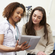 Nurse Showing Patient Test Results On Digital Tablet In Clinic Sitting Down, discussing with a young patient how to prepare for your first OBGYN visit.