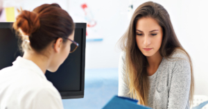 Nervous young lady at gynecology appointment with female doctor.