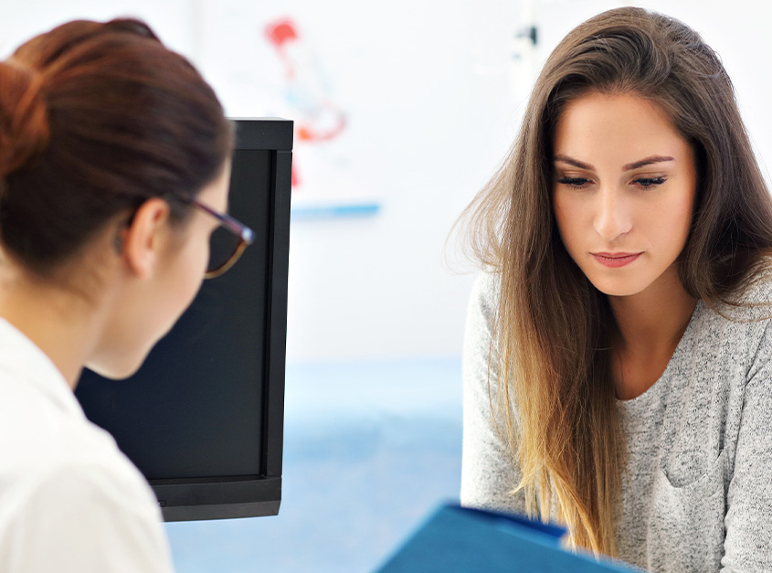 Nervous young lady at gynecology appointment with female doctor.