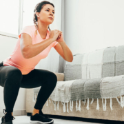 Young woman doing squats in living room