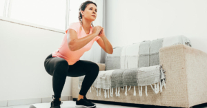 Young woman doing squats in living room