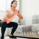 Young woman doing squats in living room