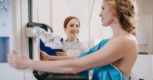 Smiling radiologist standing near patient while making mammography