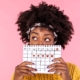 portrait of a young african american girl hiding part of her face behind a calendar