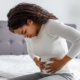 woman suffering from stomachache holding her tummy