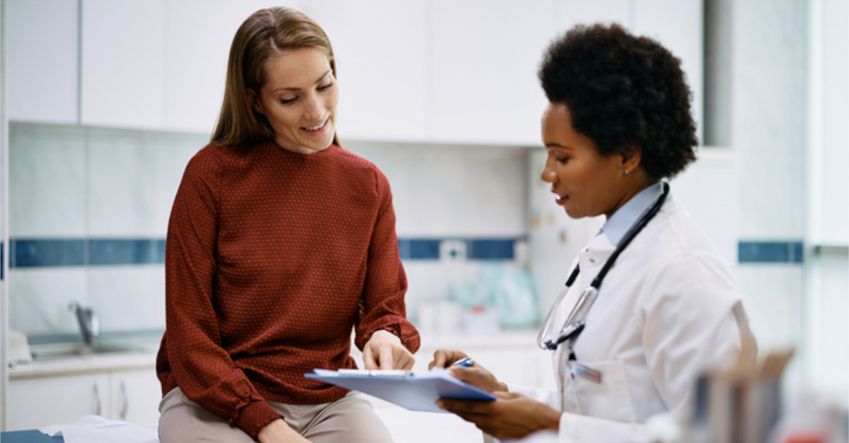 woman pointing at clipboard that doctor is holding