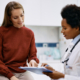 woman pointing at clipboard that doctor is holding