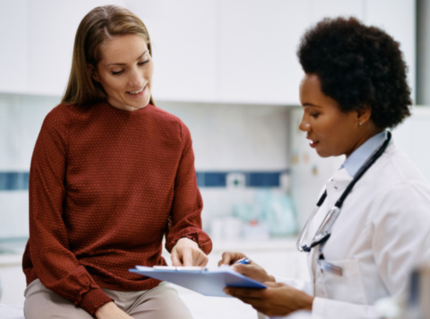 woman pointing at clipboard that doctor is holding