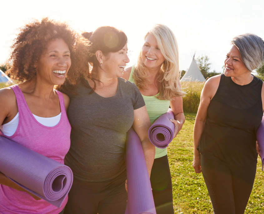 Group Of Mature Female Friends On Outdoor Yoga Retreat Walking Along Path Through Campsite