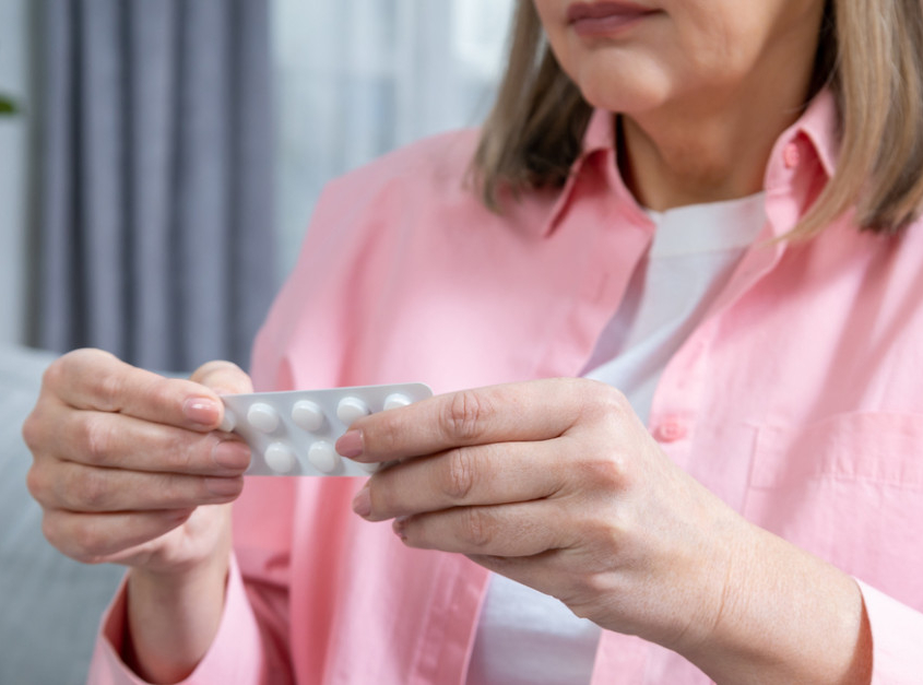 Woman wearing pink opening pills packaging